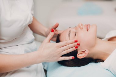 Güzel genç bir kadın güzellik salonunda yüz masajı yaptırıyor..