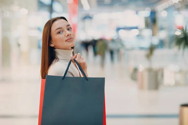 Positive young adult woman carrying paper shopping bags in hands — Stock Photo, Image