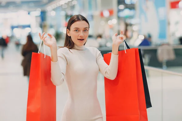 Mulher adulta jovem positiva carregando sacos de compras de papel nas mãos — Fotografia de Stock