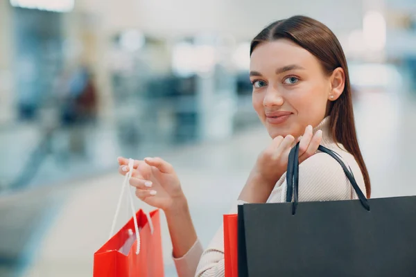 Mujer adulta joven positiva llevando bolsas de papel en las manos —  Fotos de Stock