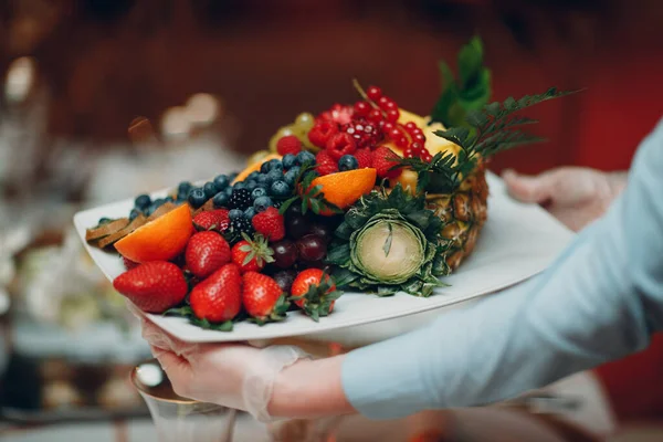 Pelayan di restoran memegang piring putih dengan buah-buahan yang berbeda stroberi beri Sehat makanan Konsep — Stok Foto