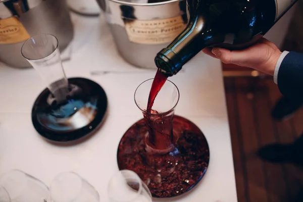 O garçom derrama vinho tinto de elite no decantador na mesa do restaurante — Fotografia de Stock