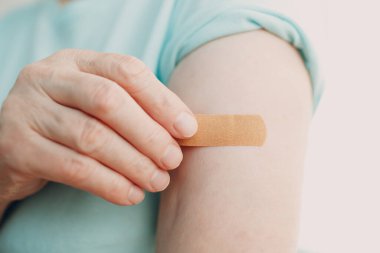 Doktor muayenehanesindeki yaşlı kadın aşısı yapışkan covid-19 aşı alçısıyla..