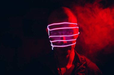 Yüzünde karanlıkta parlak tüp çizgileri olan bir adamın portresi. Sanal gerçeklik ve siber punk kavramını.