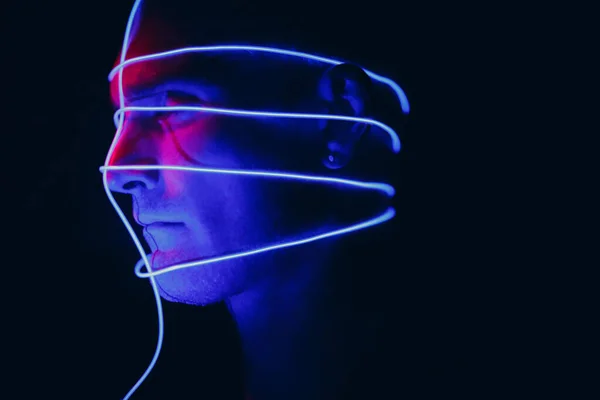 Retrato del hombre con líneas brillantes de neón en su cara. Concepto cyberpunk y realidad virtual. — Foto de Stock