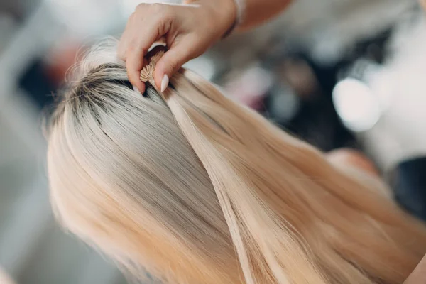 Cabeleireiro feminino fazendo extensões de cabelo para jovem mulher com cabelo loiro no salão de beleza. Extensão profissional do cabelo. — Fotografia de Stock