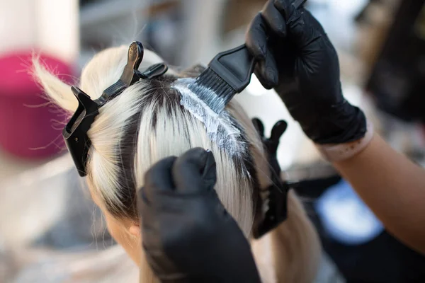 Young woman hairdresser dying hair at beauty salon. Professional hair roots coloring — Stock Photo, Image