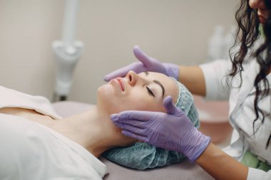 Güzellik salonunda yüz masajı yaptıran genç bir kadın.