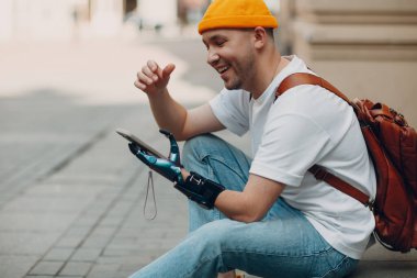 Genç engelli bir adam yapay protez eli ve cep telefonu kullanıyor..