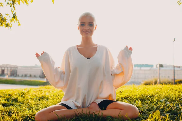 Milenyum genç bayan sarışın kısa saçlı parkta yoga lotusu yapıyor. — Stok fotoğraf