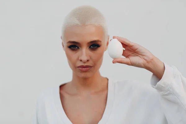 Millenial junge Frau blonde kurze Haare im Freien lächelnd Porträt mit Ei. — Stockfoto