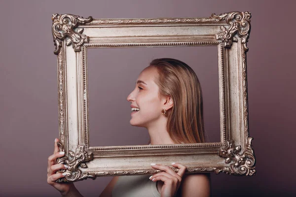 Millenial junge Frau blondes Haar hält vergoldeten Bilderrahmen in Händen Gesicht Porträt — Stockfoto