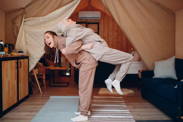 Família fazendo exercícios esportes dentro de casa. Mulher idosa jovem e sênior relaxando na tenda de campismo glamping. Mãe e filha moderna no conceito de estilo de vida de férias fitness. — Fotografia de Stock