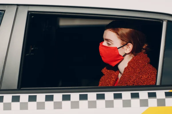 Une jeune passagère prend un taxi pendant la quarantaine pour pandémie de coronavirus. Femme portant un masque médical stérile. Distance sociale et sécurité sanitaire dans le concept de transport. — Photo