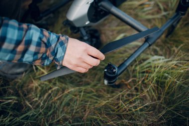 Erkek pilot, havadan uçmadan önce kuadkopter drone 'u kontrol ediyor..