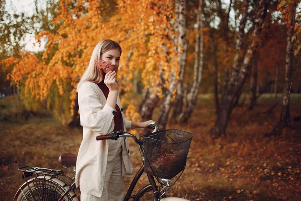 Happy active young woman riding bicycle in autumn park — Stock Photo, Image