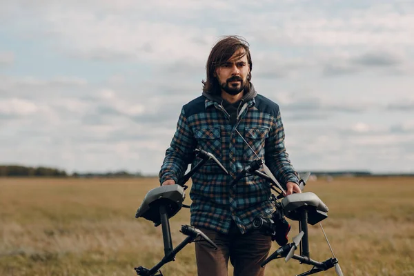 Hombre piloto sosteniendo dron quadcopter en las manos en el campo exterior. — Foto de Stock