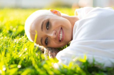 Yüzyıllık sarışın, kısa saçlı, açık havada gülümseyen genç bir kadın çimen portresinin üzerinde yatıyordu..