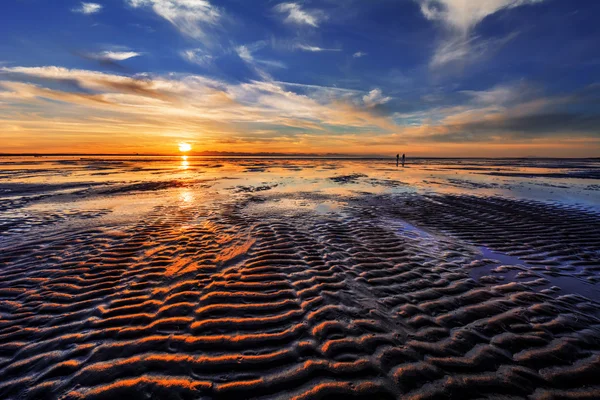 Vagues sur le sable au coucher du soleil — Photo