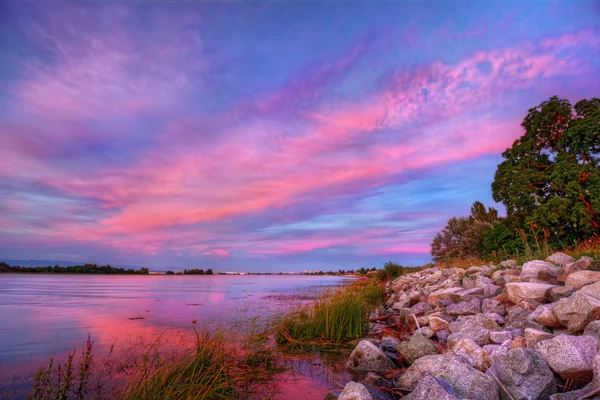 Bulutlar üzerinde kayalık riverside — Stok fotoğraf