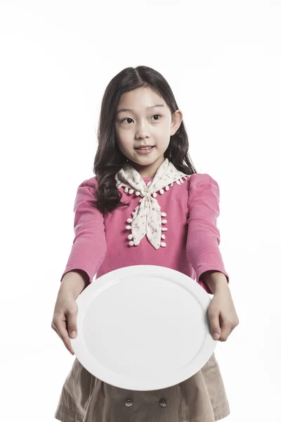 Uma menina (criança) segurando um prato branco — Fotografia de Stock