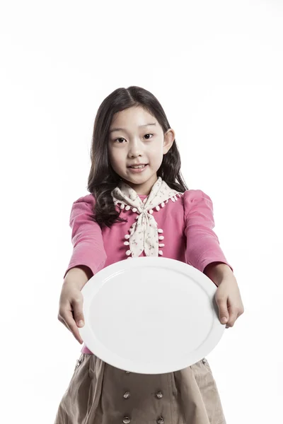 Uma menina (criança) segurando um prato branco — Fotografia de Stock