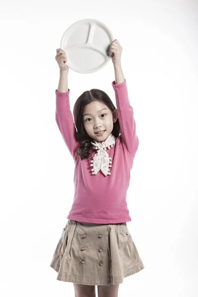 Uma menina (criança) segurando um prato branco — Fotografia de Stock