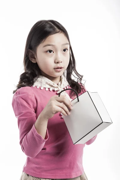 Un enfant en chemisier rose, écharpe blanche avec sac en papier . — Photo