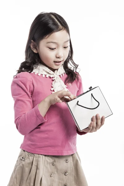 Uma criança usando blusa rosa, cachecol branco com saco de papel . — Fotografia de Stock