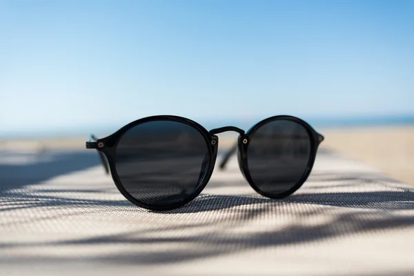 Sunglasses on a sun lounger with sea in front — Stock Photo, Image