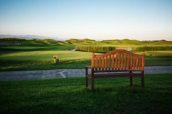 Gångväg med bänk nära golfbana vid solnedgången — Stockfoto