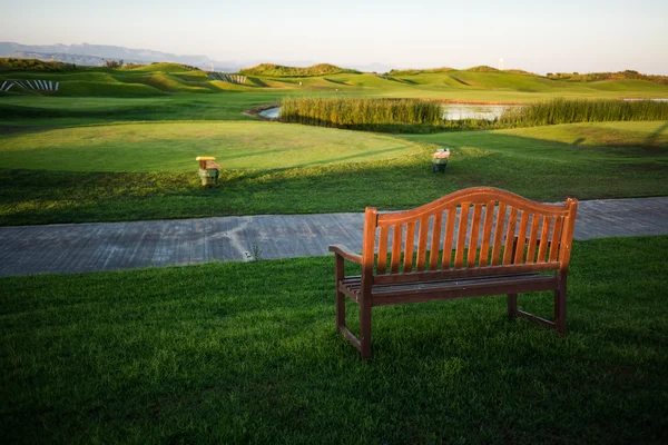 Gehweg mit Bank in der Nähe des Golfplatzes bei Sonnenuntergang — Stockfoto