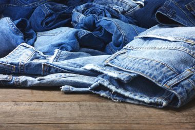 Ahşap arka planda bir yığın modaya uygun kot pantolon ve metin için yer var..                                               