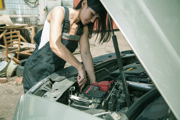  Woman car mechanician repairs engine of car 