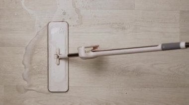 Sabun köpüğü ile ahşap zemini temizleyen bir paspas..