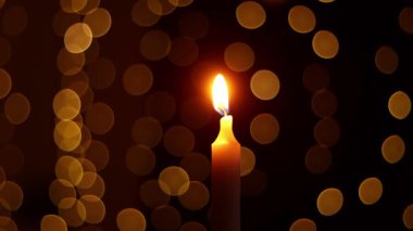 Bokeh zemin üzerinde sıcak bir parıltı ile yanan bir mum..