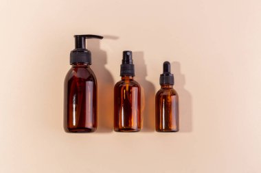 Kehribar cam cilt şişeleri. Tarafsız arka planda farklı dağıtıcılar var.