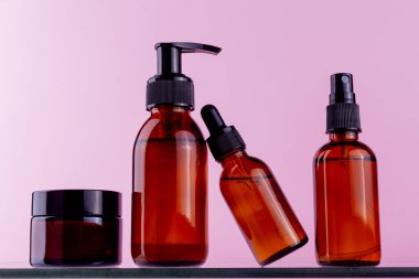 Pompa şişesi, damlalık şişesi, sprey şişesi ve kavanozdan oluşan bir kehribar cam kap koleksiyonu.