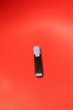 Siyah bir fıçı ve açık mavi başlıklı tek bir fosforlu kalem parlak kırmızı bir yüzey üzerinde duruyor ve basit ama çarpıcı bir kontrast oluşturuyor.