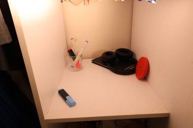 Temiz, beyaz bir rafta cam, kulaklık ve kırmızı bir disk bulunur. Yaratıcı çalışmaya ya da çalışmaya hazırdırlar.