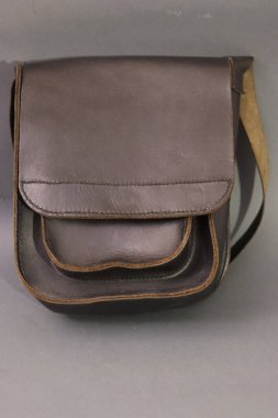 İçinde güvenli bir kapak kapağı ve şık katmanlı ön cep tasarımı bulunan, günlük kullanım için mükemmel, ebedi koyu kahverengi deri bir kurye çantası.