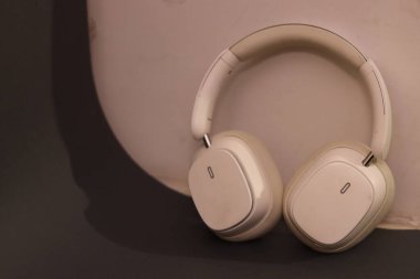 Pürüzsüz, minimalist estetik kulaklıklı bir çift beyaz kulaklık nötr tonlu bir yüzeye yerleştirilmiştir. Temiz çizgilerini ve çağdaş tarzlarını ön plana çıkarırlar.