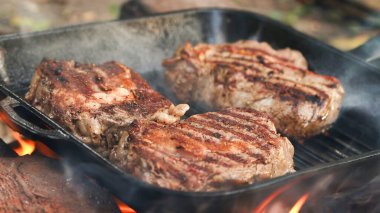 Kalın et kesikleri, dökme demir bir tavada ustalıkla kızartılır, aromatik buhar yayar ve alevlerin altındaki güzel yanık izlerini gösterir.