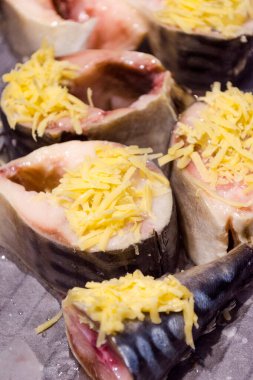 Çiğ uskumru, fırın tepsisinde peynirli dilimler.