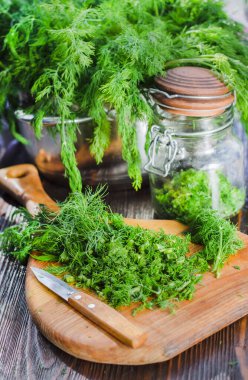 Mutfak tahtasının üzerinde dilimlenmiş taze dereotu. Taze kesilmiş yeşiller