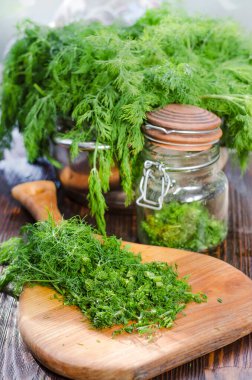 Mutfak tahtasının üzerinde dilimlenmiş taze dereotu. Taze kesilmiş yeşiller