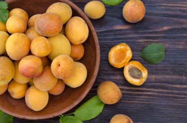 Tahta bir masada yaprakları olan taze, olgun organik kayısılar.