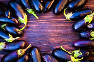 Masanın etrafında kavrulmuş olgun mor patlıcanlar. Masanın içinde boş yer var.