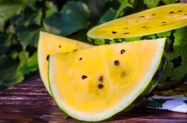 Sarı posalı karpuz. Tahta bir masada dilimlenmiş böğürtlen parçaları..