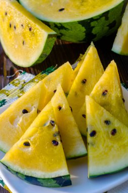 Sarı posalı karpuz. Tahta bir masada dilimlenmiş böğürtlen parçaları..
